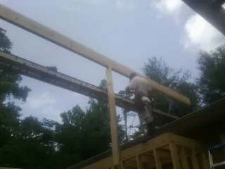 Carpenter setting a ridge beam over a new addition frame — Ice Dam Removal by Roofing Brothers in Riddleton
