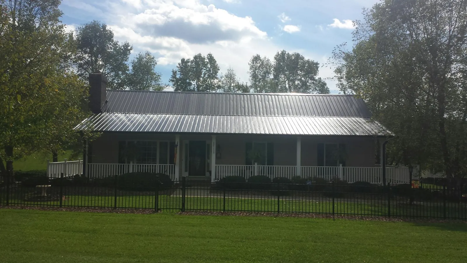 Gray metal roof on a brick ranch with a full width front porch — Gutter Guard Installation work by our crew in Riddleton