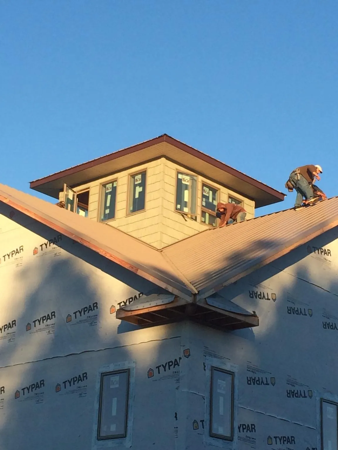 Roofers working around a rooftop cupola on a new metal roof at sunset — Roof Waterproofing in Riddleton by Roofing Brothers